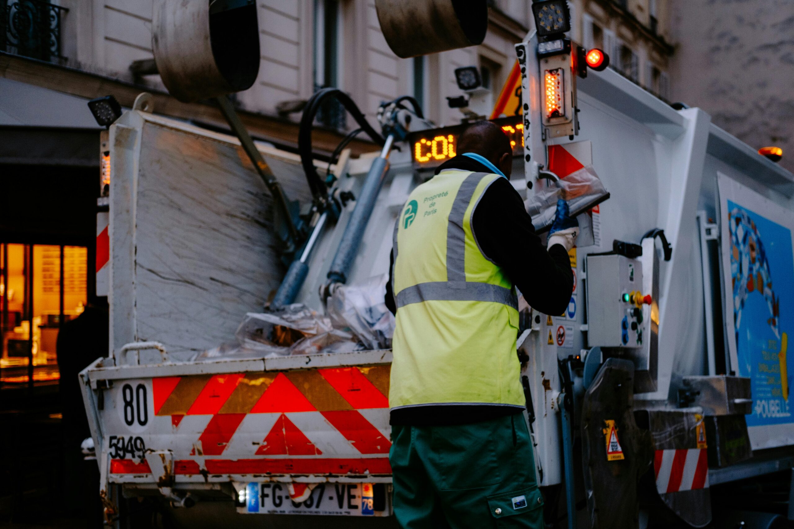 vuilnisman achterop een vuilniswagen